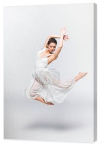 piękna młoda baletnica tańczy w białej sukni na szarym tle
