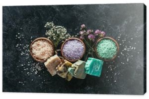 Widok z góry domowej roboty mydła, suszone kwiaty i sól morska w drewniane miski na czarnej powierzchni marmuru