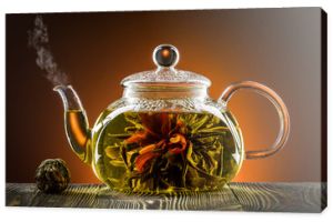 Szklany czajniczek z kwitnącym kwiatem herbaty na drewnianym stole