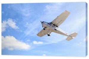 Samolot ultralekki lecący na niebieskim niebie z białymi chmurami