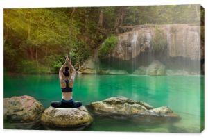 Piękna kobieta praktykowania jogi na skale w pięknym wodospadzie.