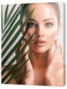 Młoda piękna kobieta z zielonymi liśćmi w pobliżu ciała. Koncepcja zabiegów kosmetycznych pielęgnacji skóry. Zbliżenie twarzy dziewczyny z zielonymi liśćmi.