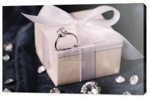 Selektywny fokus pierścionek zaręczynowy na pudełko z kokardą w pobliżu błyszczące diamenty na niebieski tkaniny