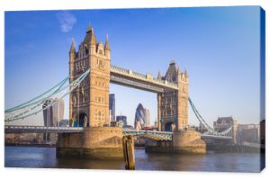 Londyn, Anglia – słynny most Tower Bridge w porannym słońcu z czerwonym autobusem piętrowym i dzielnicą bankową w tle