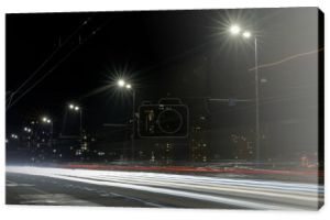 Długa ekspozycja świateł drogowych w nocy w pobliżu oświetlonych budynków