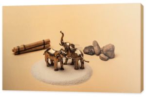 Słonie zabawki na piasku z kamieni i drewniane kije na żółtym tle, koncepcja dobrostanu zwierząt