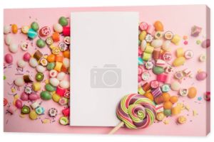 Widok z góry pyszne cukierki wielokolorowe, lizak i biała karta z kopią przestrzeni na różowym tle