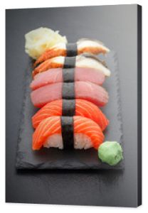 Nigiri sushi ustawione na kamiennej płycie na czarnym tle