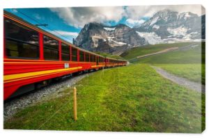 Kolejka górska z popularnym elektrycznym czerwonym pociągiem turystycznym. Góra Jungfrau z godnymi podziwu lodowcami i czerwonym pociągiem pasażerskim, Grindelwald, Bernese Oberland, Szwajcaria, Europa