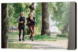 selektywnej ostrości uśmiechniętego dojrzałego sportowca i Sportsmen biegną razem w parku