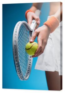 przycięty widok sportowej młodej kobiety trzymającej rakietę tenisową i piłkę podczas gry na niebiesko