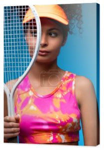 sportowa młoda kobieta odwraca wzrok trzymając rakietę tenisową na niebiesko