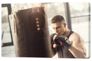 lekkoatletycznego młody człowiek w Rękawice bokserskie, szkolenia z workiem w siłowni