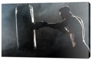sylwetka sportowca w Rękawice bokserskie uderzenie workiem na czarne, z dymu
