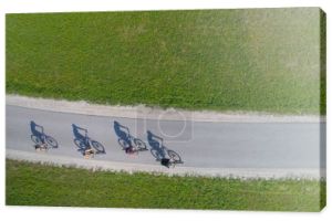 TOP DOWN: Czterech przyjaciół jazda na rowerach rzuca cienie na pustej asfaltowej drodze.
