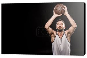 koszykarz mięśni, rzucając piłkę na czarnym tle 