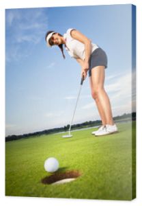 Szczęśliwa dziewczyna golfista wprowadzenie piłki do dołka.