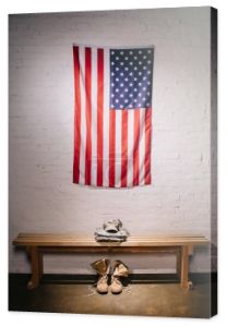 Widok z amerykańską flagę, wiszące na ścianie biały cegła i ułożone, wojskowy mundur na ławeczce, drewniane, z bliska