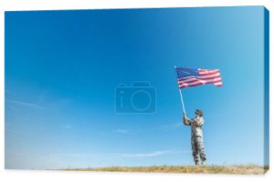 przystojny wojskowy mężczyzna w mundurze patrząc na amerykańską flagę z gwiazdami i paskami 