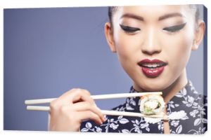 Kobieta sushi trzymająca sushi pałeczkami patrząca w kamerę