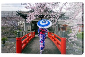 Azjatycka kobieta ubrana w japońskie tradycyjne kimono i kwiat wiśni na wiosnę, świątynia Kioto w Japonii.